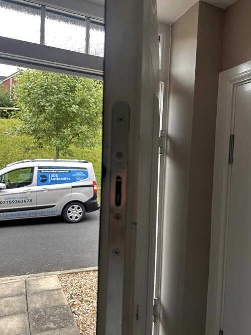 Open uPVC door showing the lock mechanism with the SOS Locksmiths van parked outside
